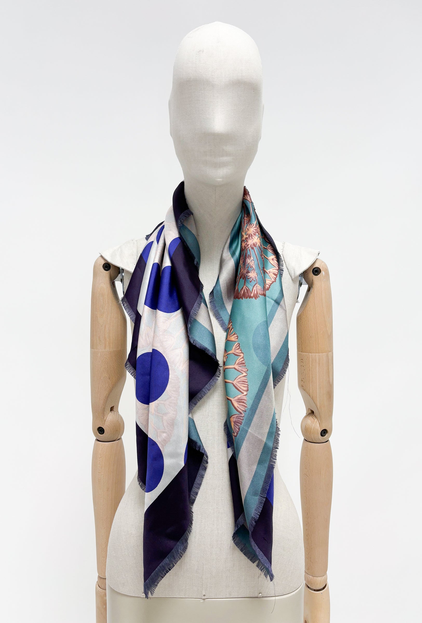 Odeeh Seidentuch mit abstrakten, floralem Print in  verschiedenen blau Tönen - um den Hals einer Puppe gelegt  