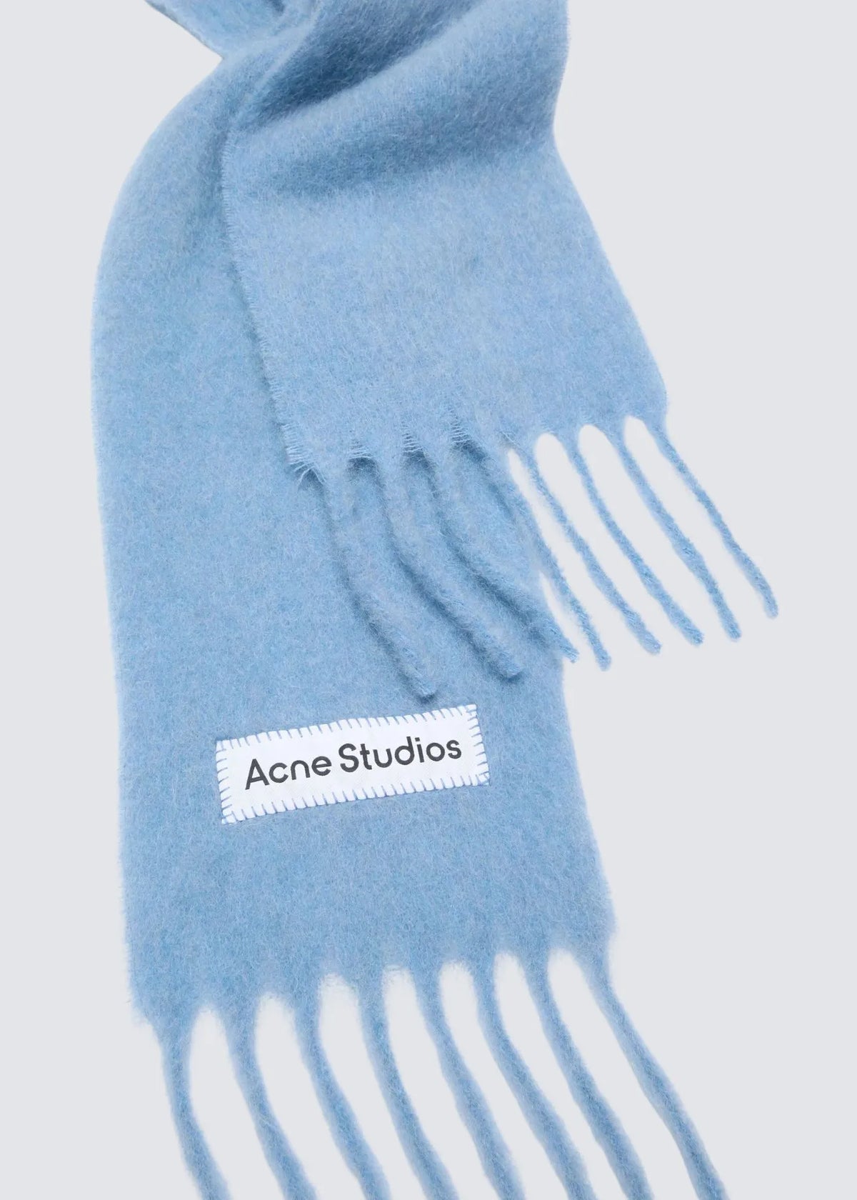 Detailshot des weißen Logos mit schwarzer Acne Studios Aufschrift und den fransigen Enden.