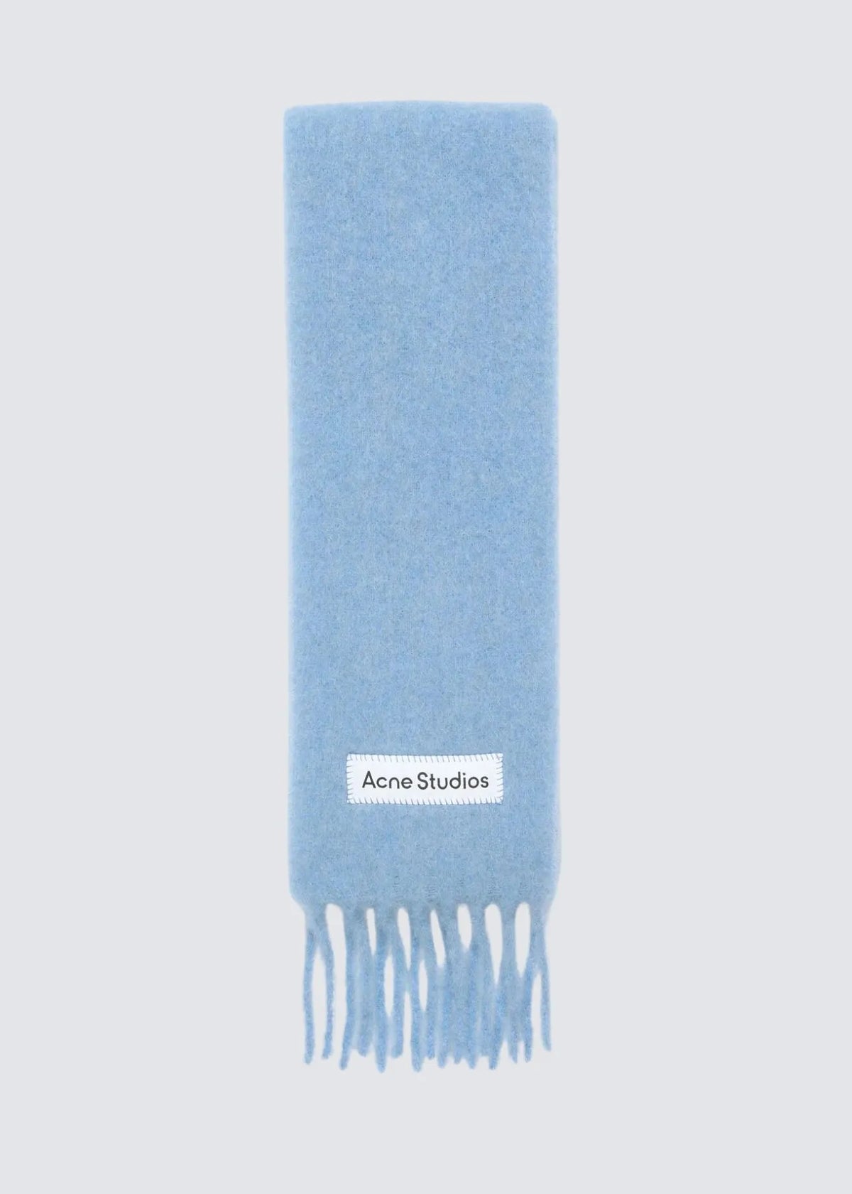 Hellblauer schmaler Schal von Acne Studio mit einem Weißen Logo aus Satin welches Im Festonstich aufgenäht wurde. die Enden sind fransig.