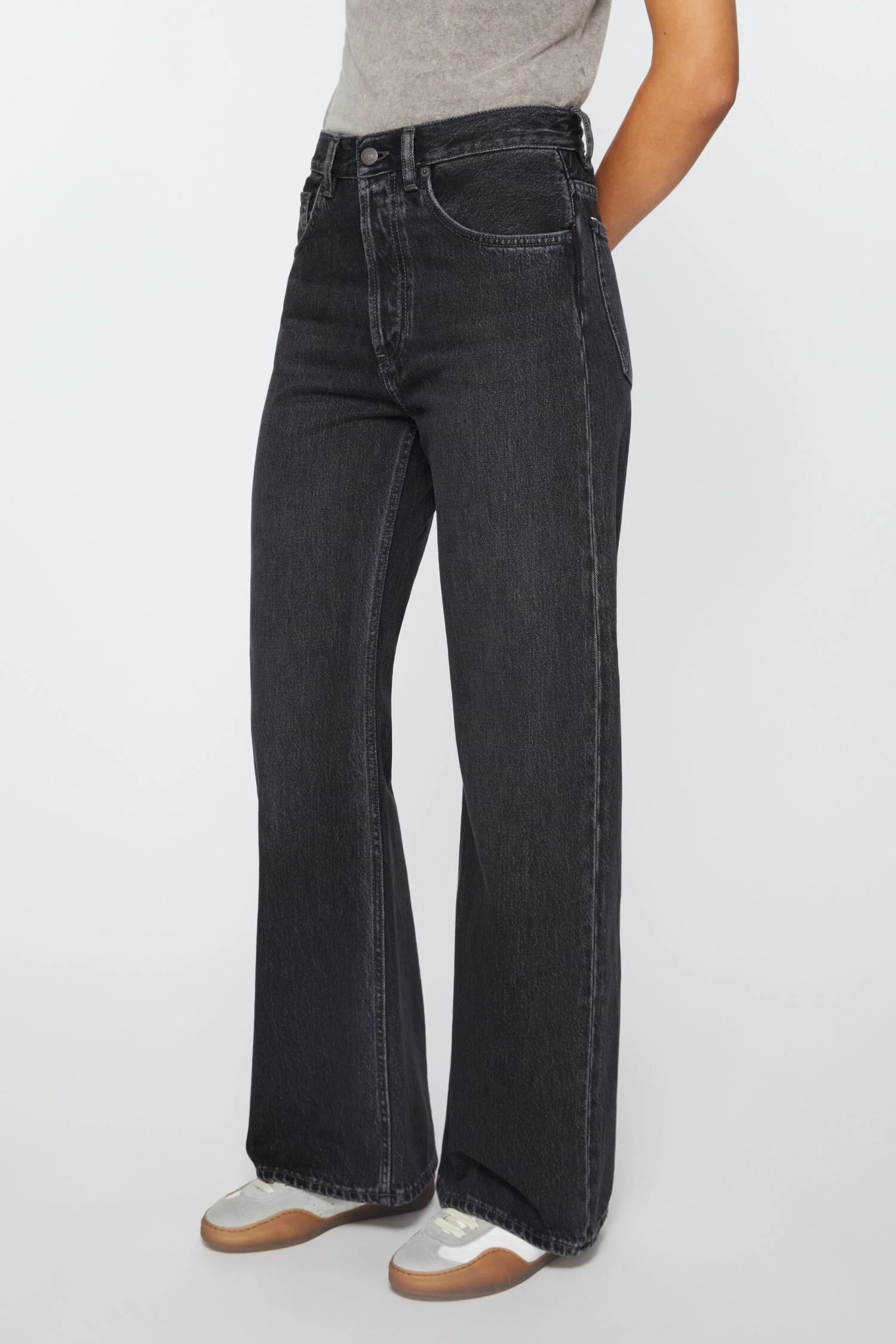 Schwarz mellierte Jeans, mit einem geraden Bein und einer mittleren Bundhöhe. Dreiviertel Shot.