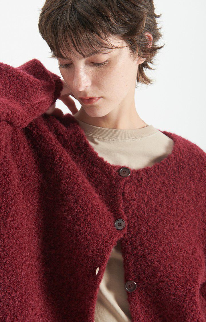 Cardigan am Model in der Detailansicht. Der rechte Arm ist angewinkelt, der Cardigan ist nur an den oberen beiden Knöpfen zugeknöpft. 