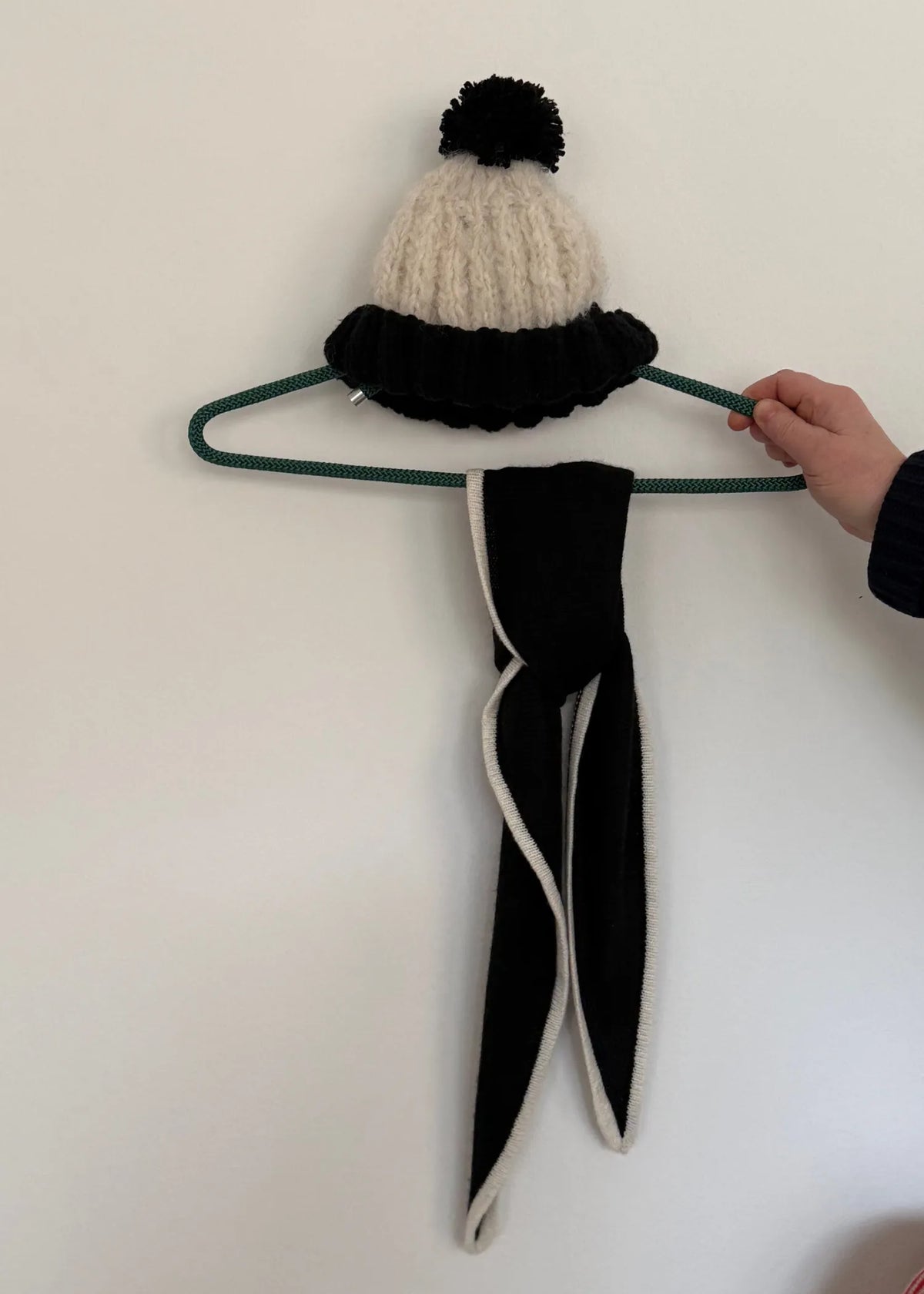 Strickmütze mit Tuch kombiniert an einem Kleiderhaken.