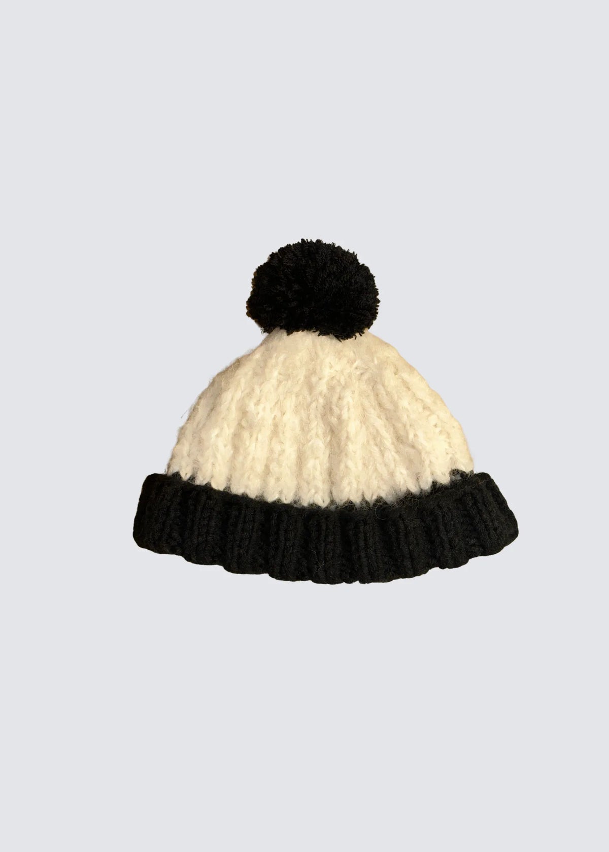 Balcon Preysing handgestrickte Mütze in schwarz / weiß mit Bommel. Freistehend abgelichetet.