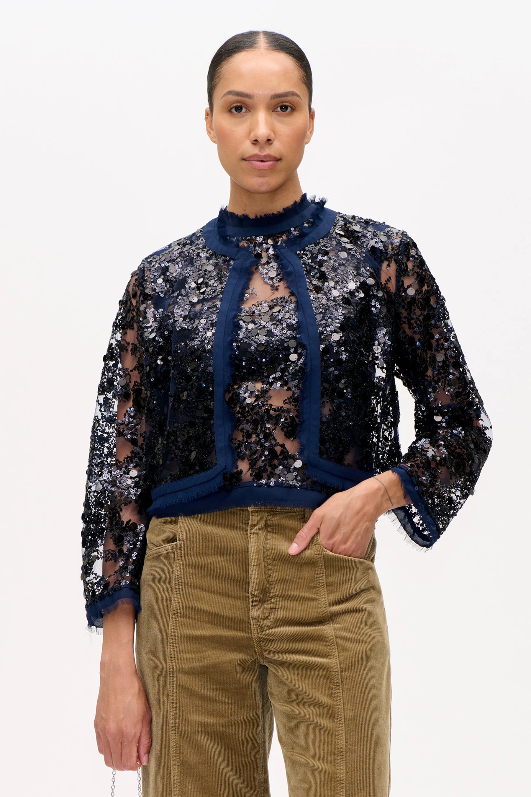 Kastig geschnittene Semitransparente Pailletten-Jacke in Dunkelblau mit Rundhalsausschnitt.
Model Bild Dreivirtelansicht..