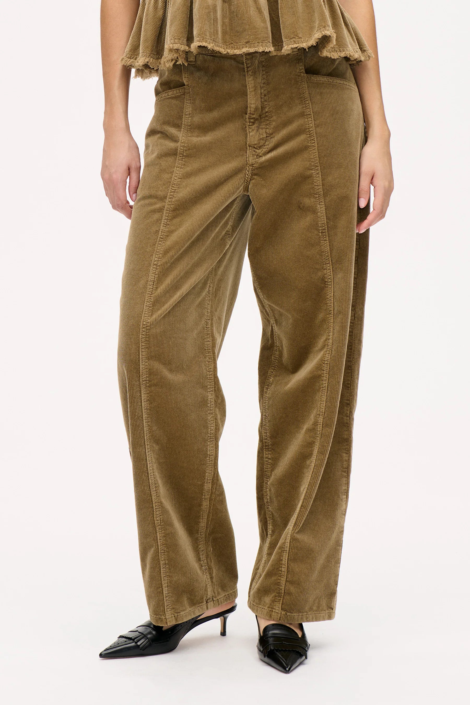 High Waist Cordhose mit Knopf- und Reißverschluss sowie Gürtelschlaufen. Ziernähte vorn und hinten.  Weites, gerades Bein. Model Bild Beinausschnitt.