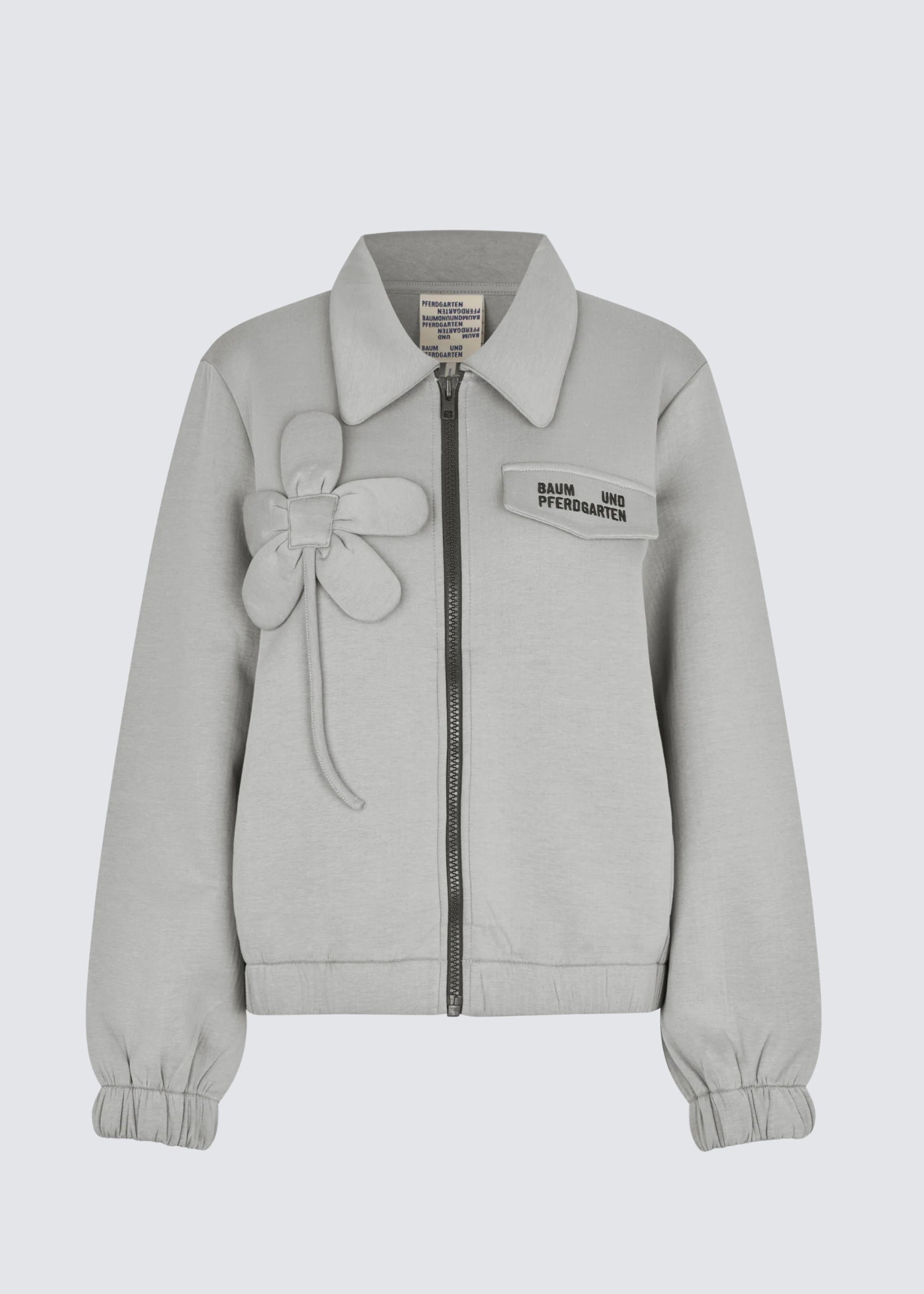 Graue Zipper Jacke, mit aufgenähtem Blumendetail. Flat Shot.