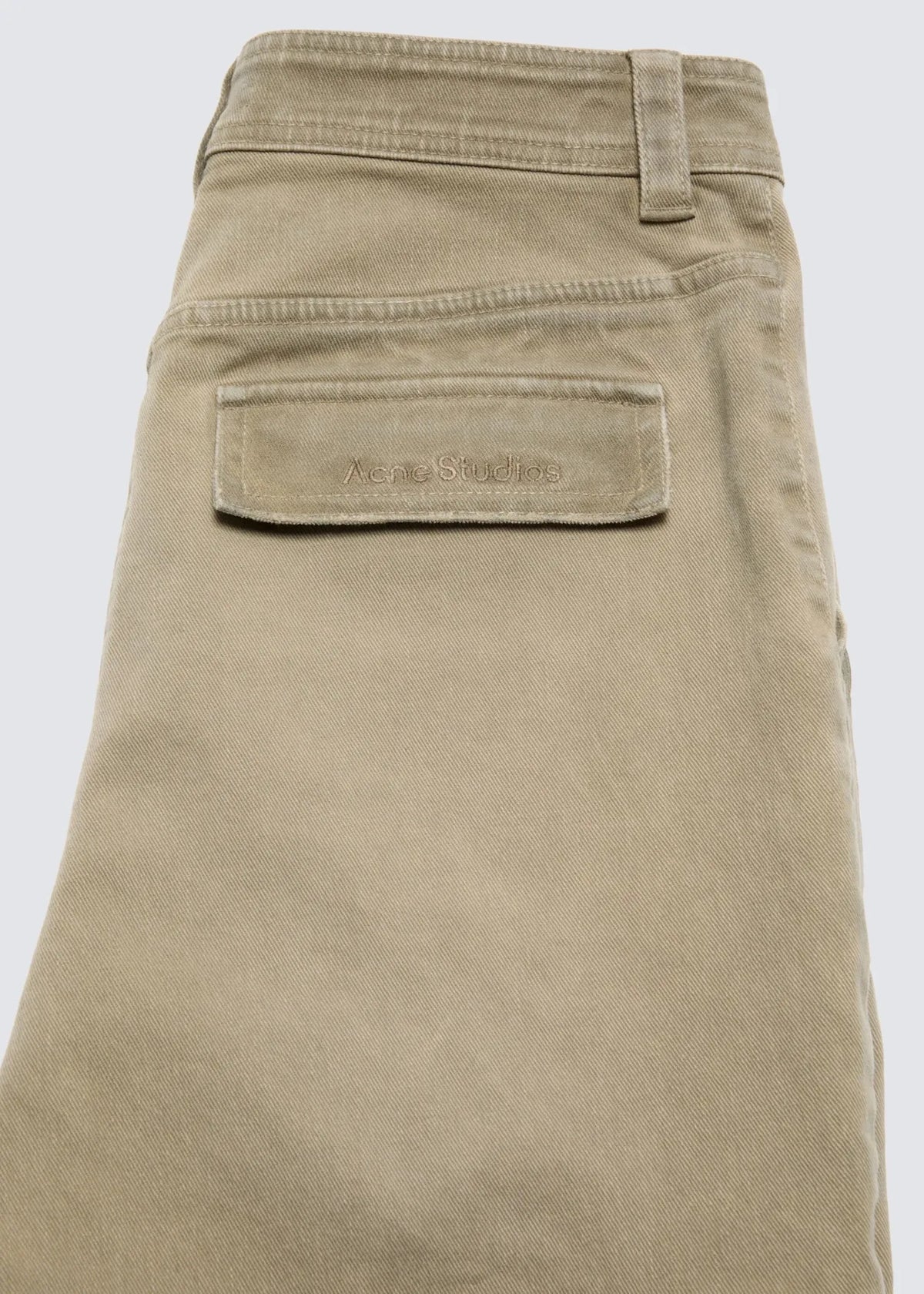 Fokus auf die Hintertasche der beigen Hose mit Acne Studios Logo Stickerei.