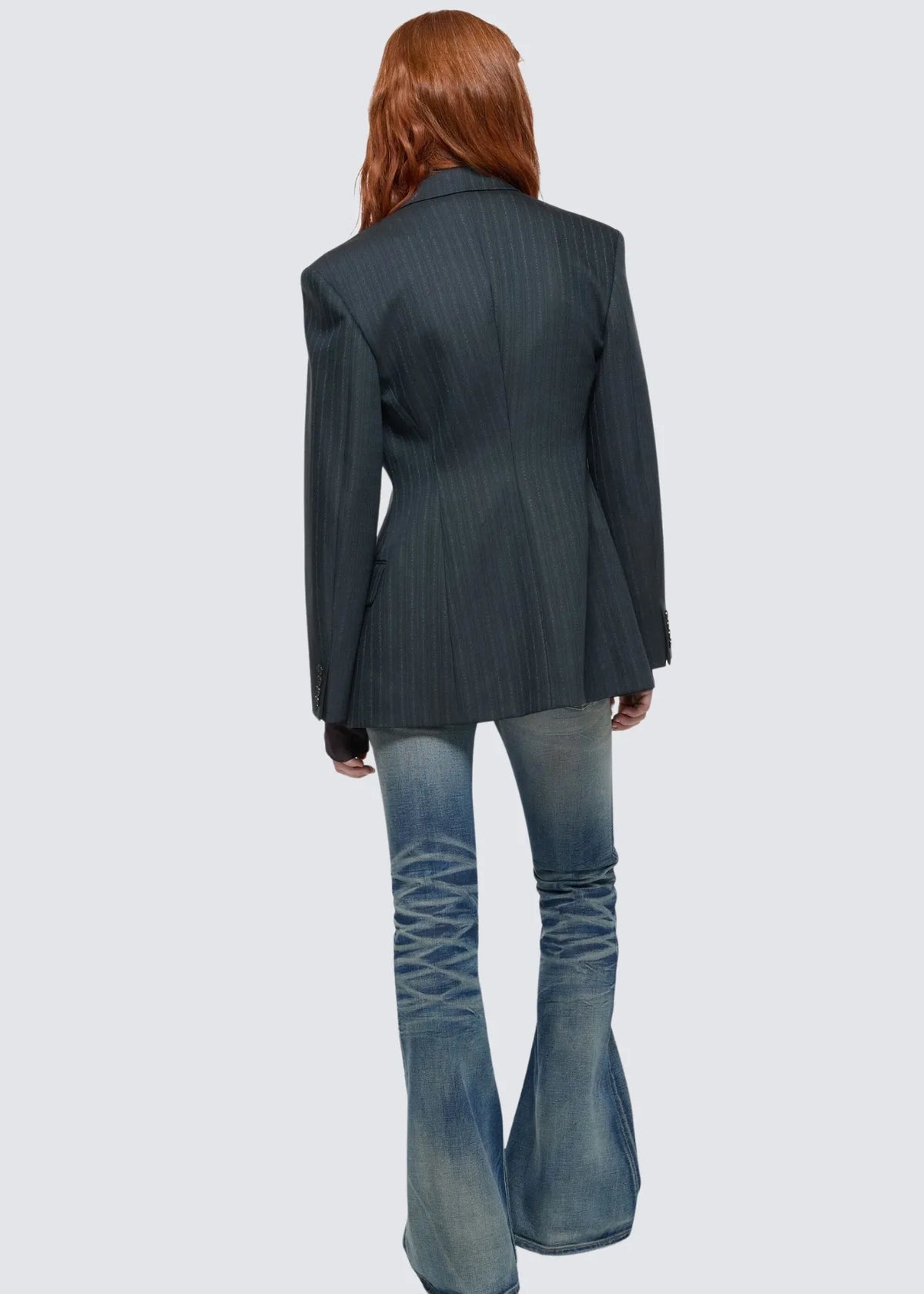 Modellfototo der Anzugjacke von hinten vor hellem Hintergrund. Die Jacke ist tailliert und erzeugt mit einer Jeanshose kombiniert einen edlen Eindruck.