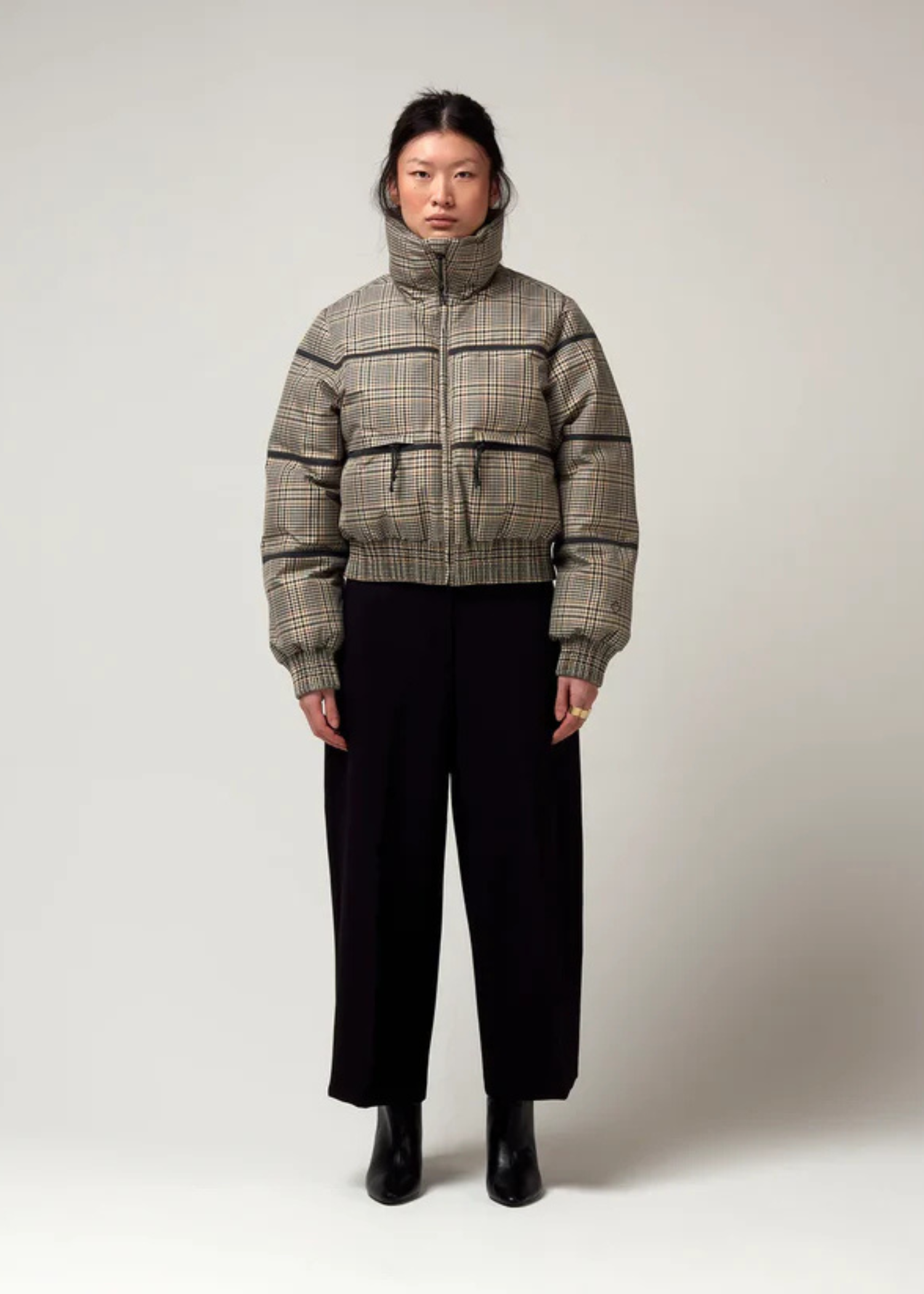 Bomberjacke mit Stehkragen, Reißverschluss und Zwei Taschen. Saum an Ärmeln sowie Bauch mit Gummizug. Karo Muster in Beige Braun. Model Bild.