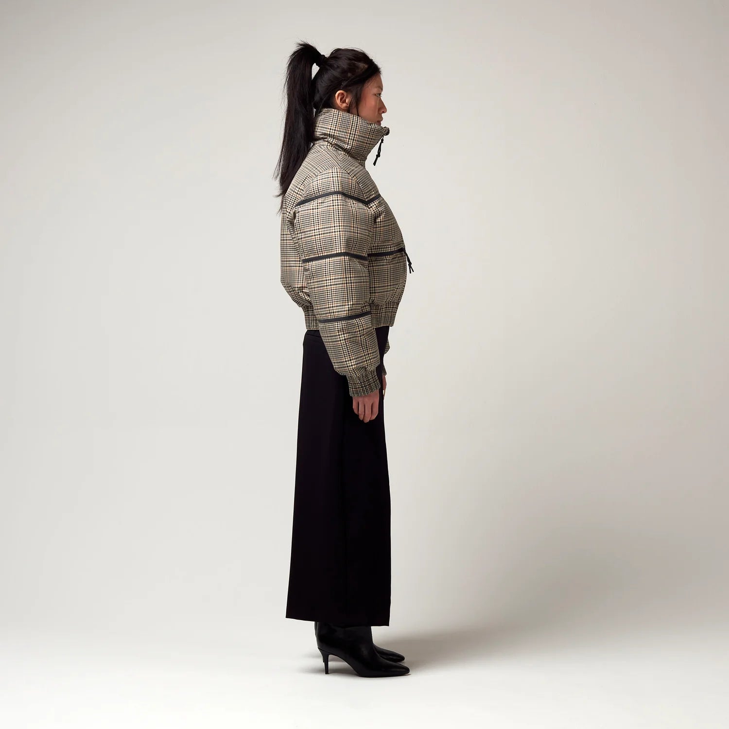 Bomberjacke mit Stehkragen, Reißverschluss und Zwei Taschen. Saum an Ärmeln sowie Bauch mit Gummizug. Karo Muster in Beige Braun. Model Bild, seitliche Ansicht.