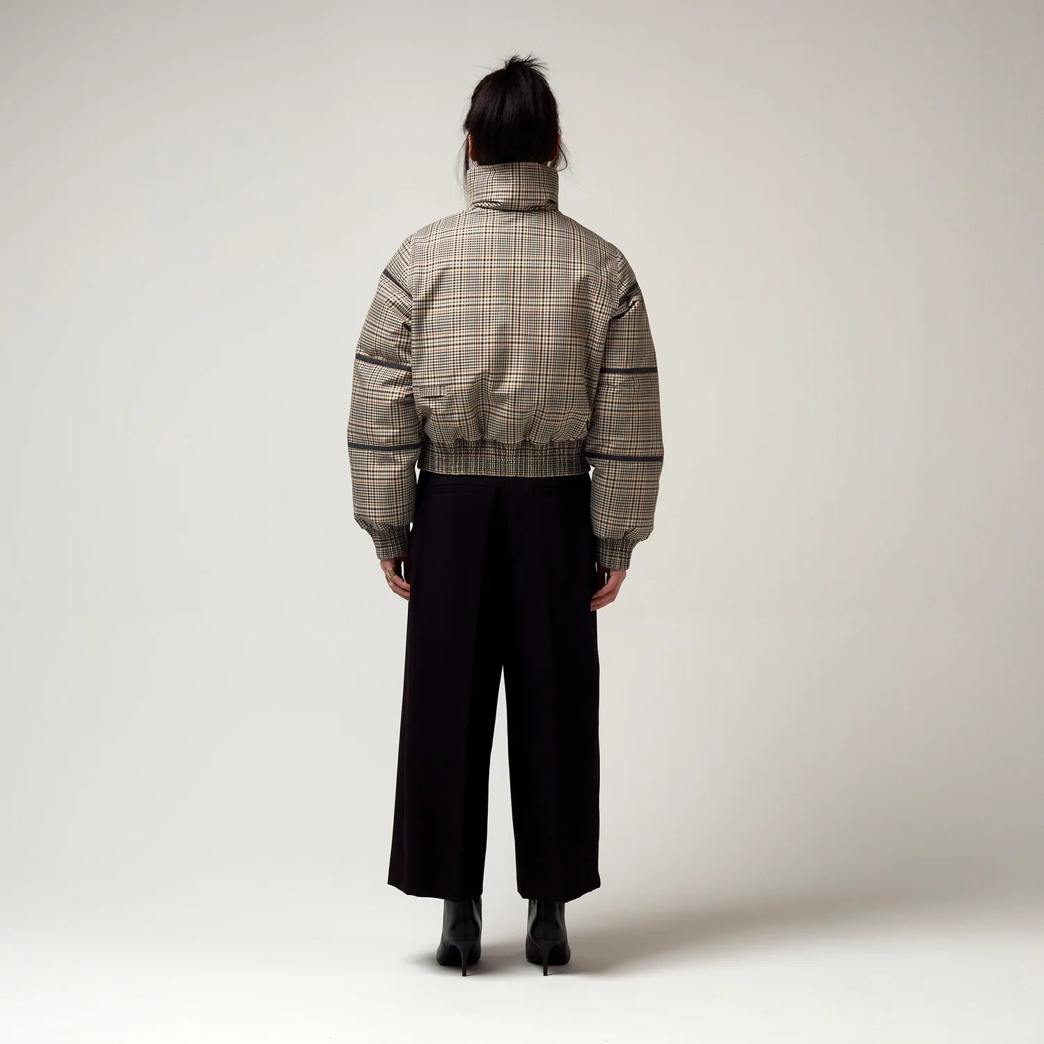 Bomberjacke mit Stehkragen, Reißverschluss und Zwei Taschen. Saum an Ärmeln sowie Bauch mit Gummizug. Karo Muster in Beige Braun. Model Bild, Rückseite.