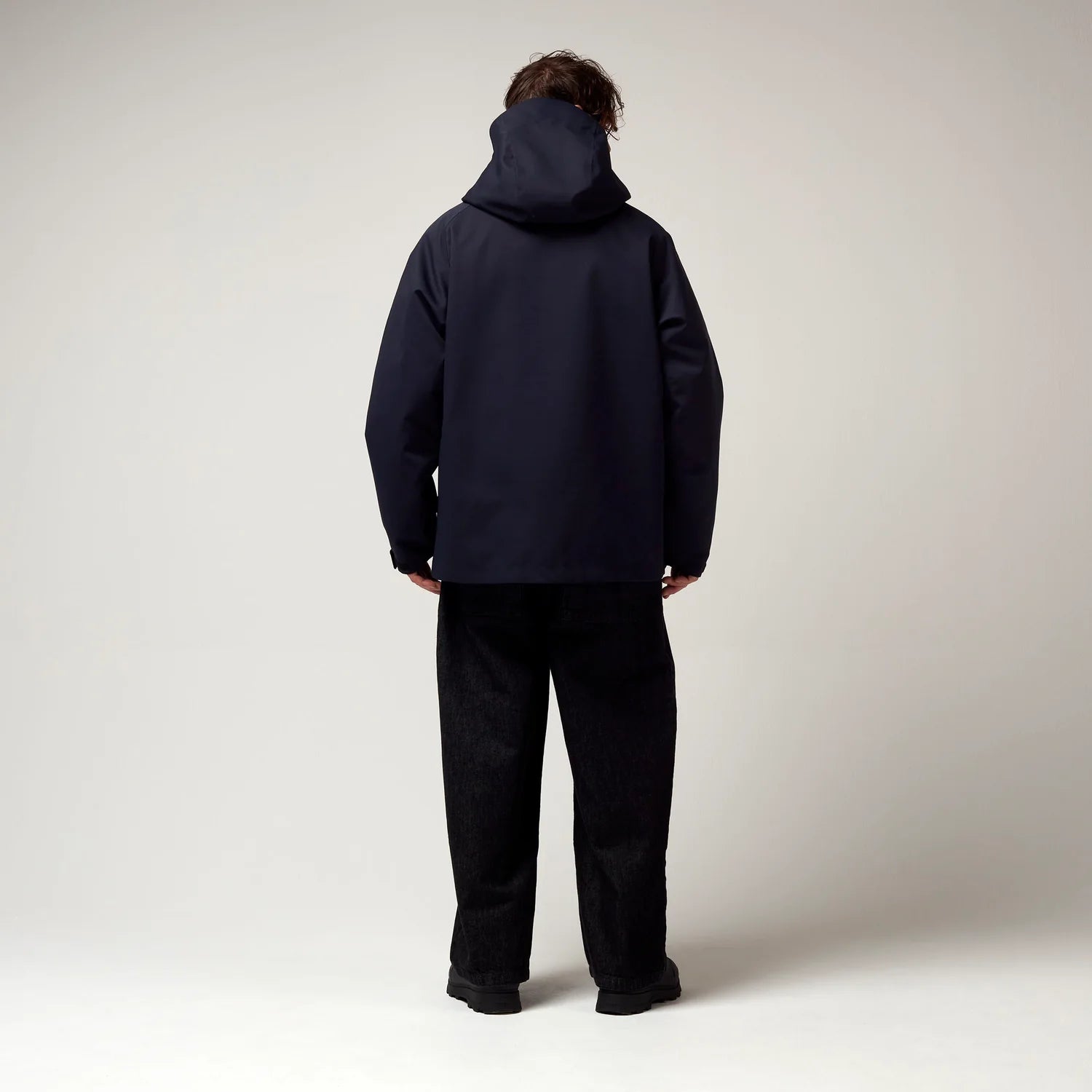 Dunkel Blaue  kurz geschnittene Jacke, mit Verstellbarer Kapuze sowie verstellbarem Saum an den Händen. Schwarze Hardware. Model Bild, Rückseite.