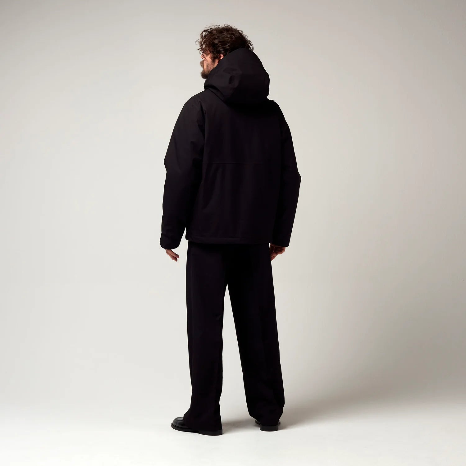 Kurz geschnittene Schwarze Jacke, mit verstellbarer Kapuze, seitlichen Jacke Taschen sowie schwarzer Hardware. Saum an den Ärmeln mit Daumen Loch. Model Bild, Rückseite.