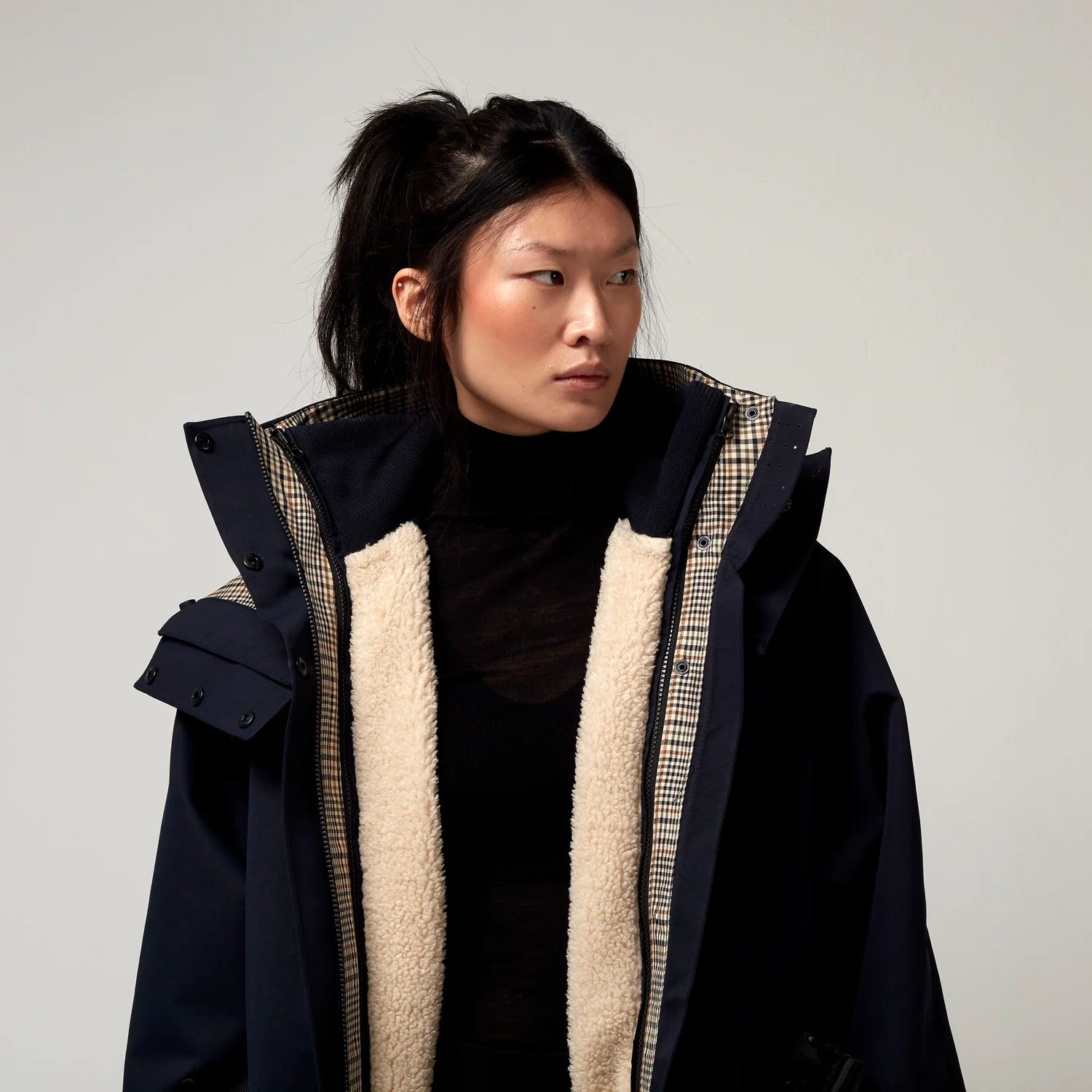 Dunkel Blauer Parker, mit Verstellbarer sowie abnehmbarer Kapuze. Innenjacke durch Druckknopf Befestigung mit Fütterung zu erkennen. Model Bild, Detail Aufnahme.