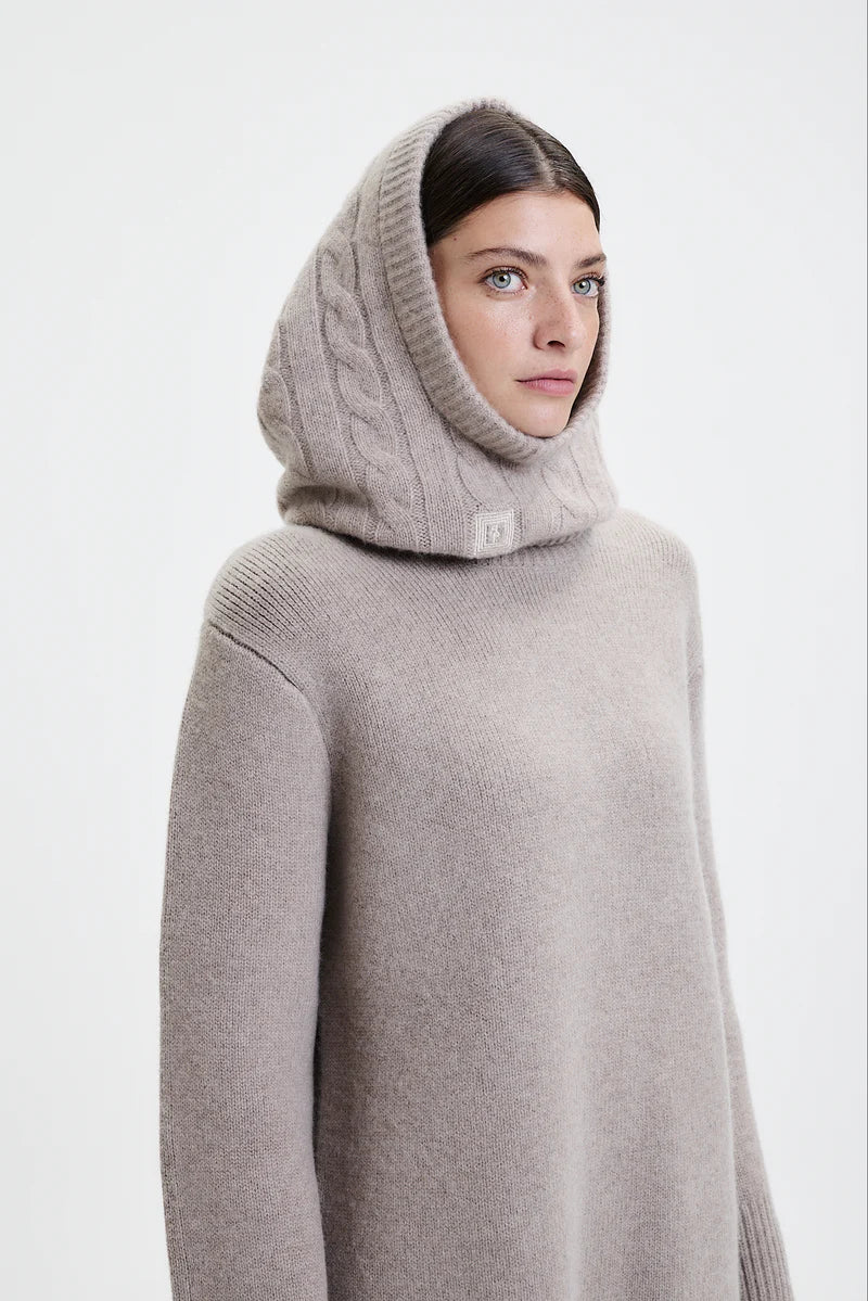 Prinz Berlin Kaschmir Balaklava in taupe mit Rippenstrick Optik. Das Model trägt die Balaklava zusammen mit einem beigen Pullover. Portrait des Models, seitlich.