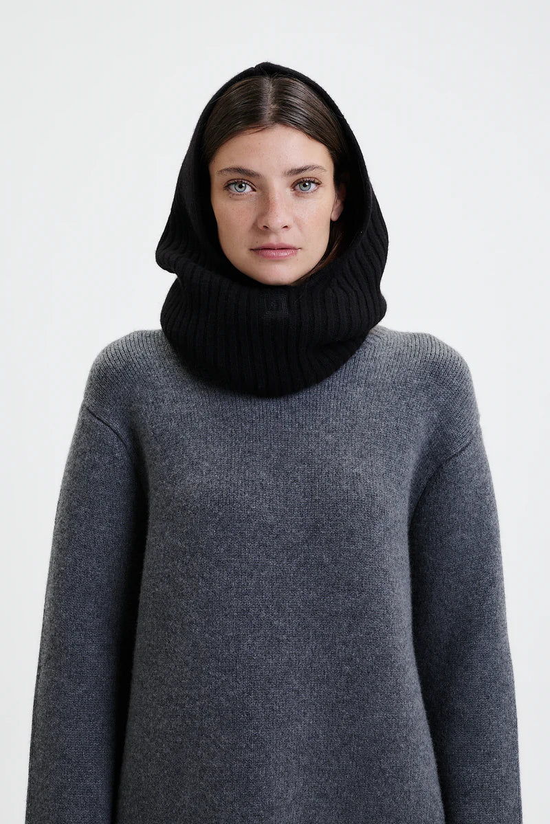 Prinz Berlin Kaschmir Balaklava in schwarz mit Rippenstrick Optik. Das Model trägt die Balaklava zusammen mit einem grauen Pullover. Portrait des Models.