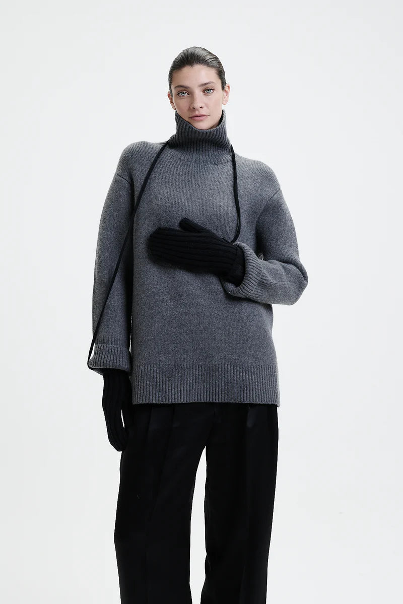 Prinz Berlin schwarze Mittens mit Rippenstrick. Model trägt die Handschuhe und hat die Kordel um den Hals gebunden. Portrait Ansicht des Models.