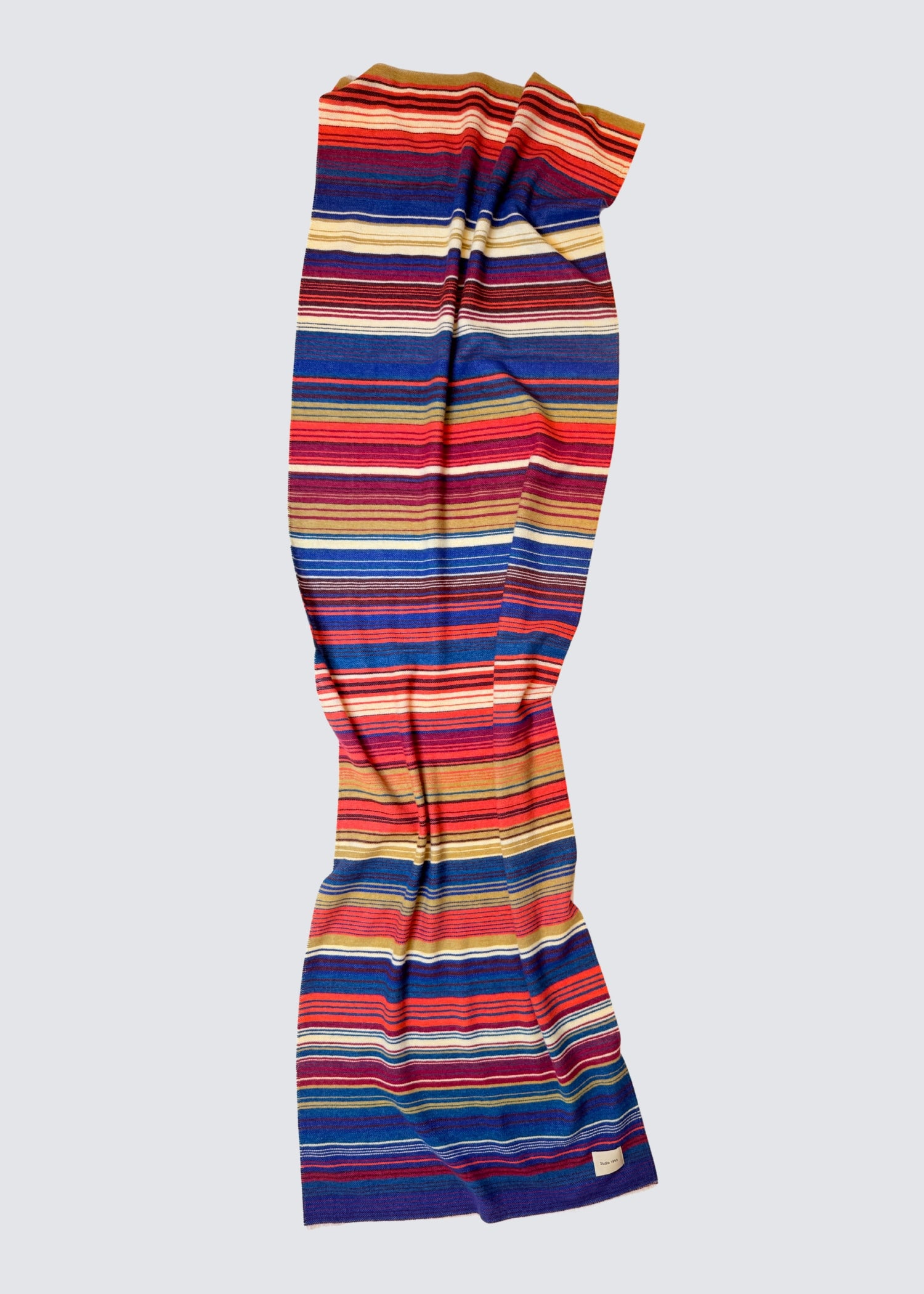 studio 1893 100% Wollschal, mit ausgefranstem Saum. Bunt gestreift. Ocker und Dunkelblau. Flatshot, ausgebreitet.