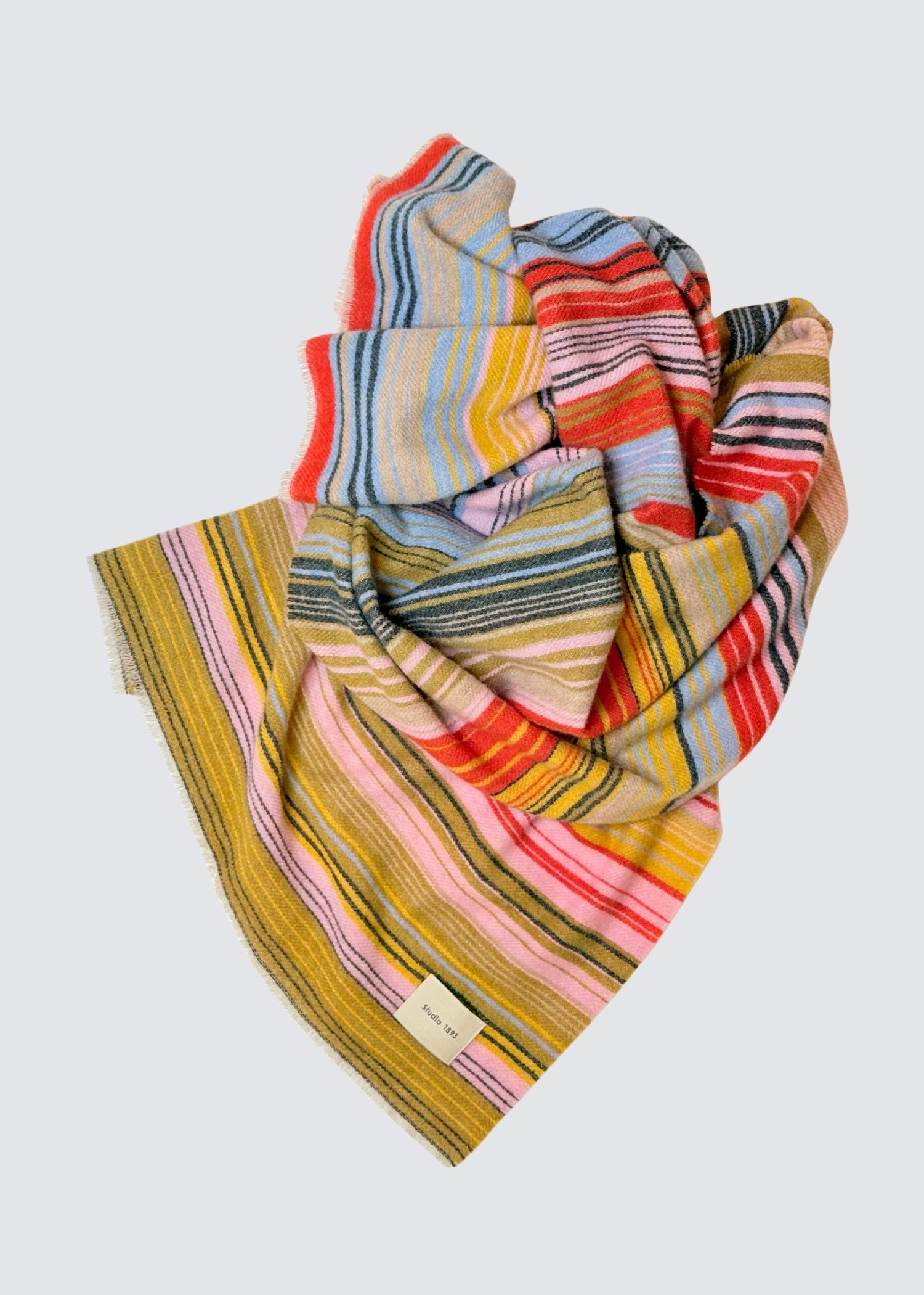 studio 1893 100% Wollschal, mit ausgefranstem Saum. Bunt gestreift. Gelb, grün, rot, blau. Hellere frischere Farben. Flatshot, zusammengelegt.