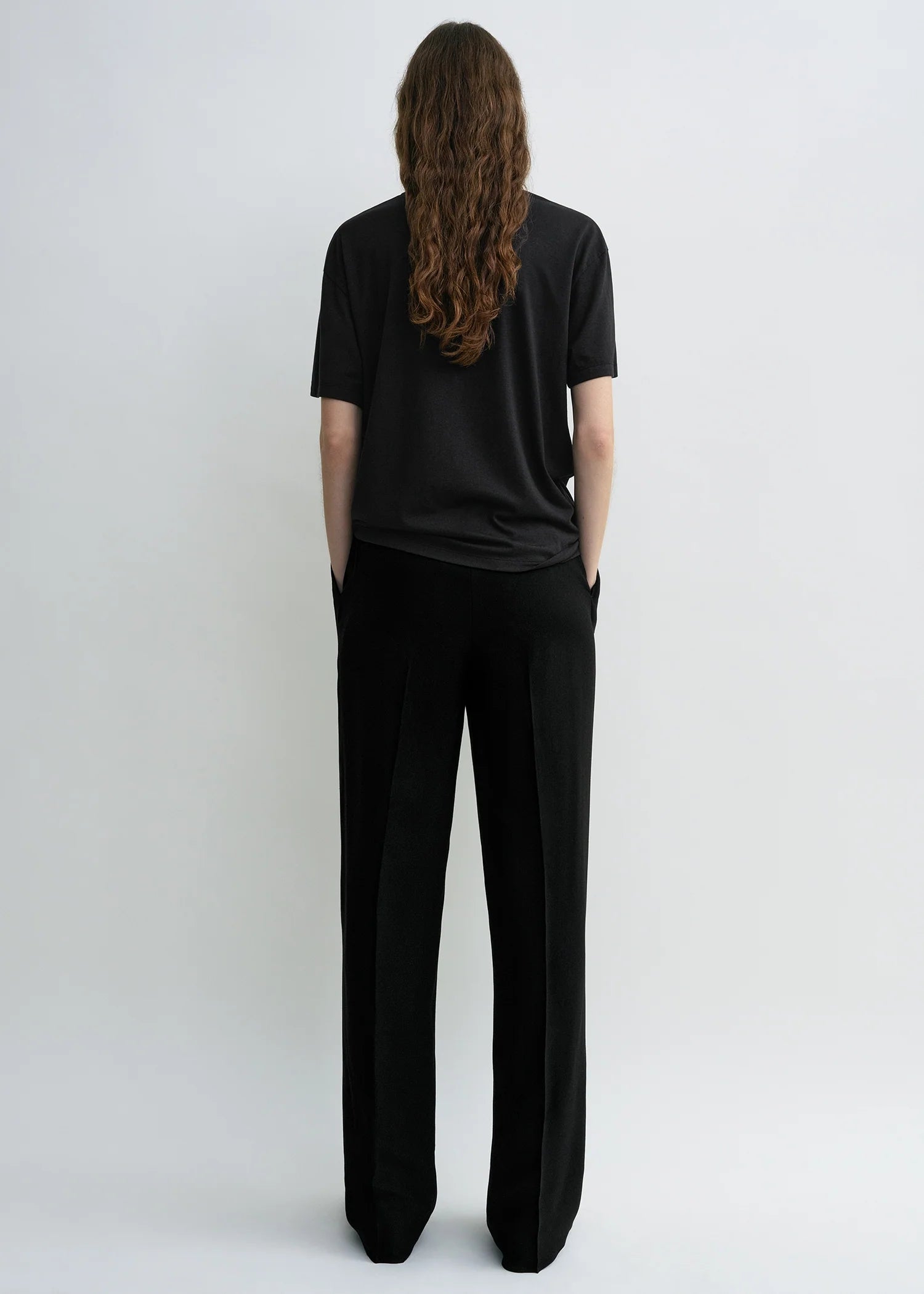 Schwarzes T-Shirt mit Rundhalsausschnitt. Model Bild, Rückseite.