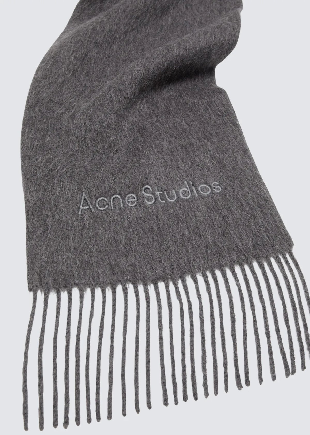 Fokus auf die Acne Studios Logo-Stickerei sowie das fransige Ende des Schals.