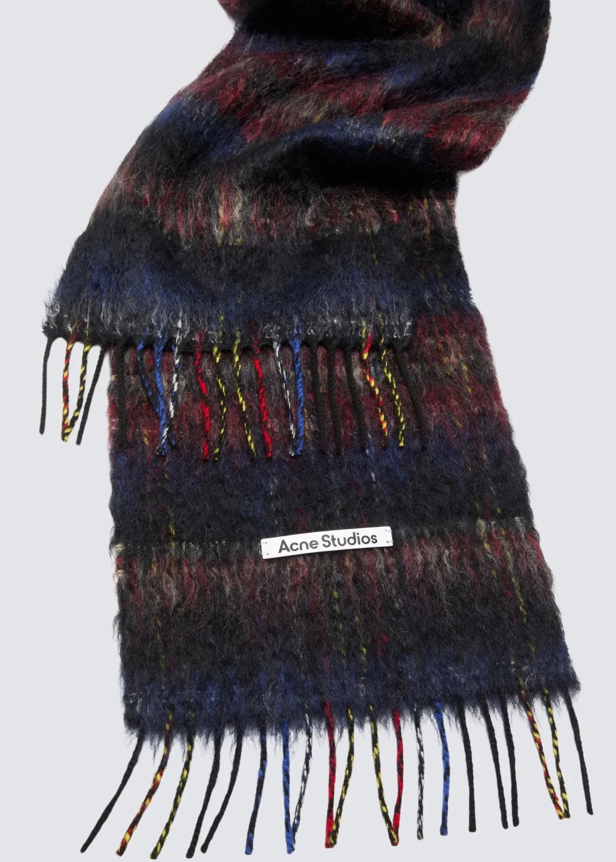 Nahaufnahme mit Fokus auf den Acne Studios Aufnäher in weiß mit schwarzem Marken Schriftzug sowie die ausgefransten Enden.