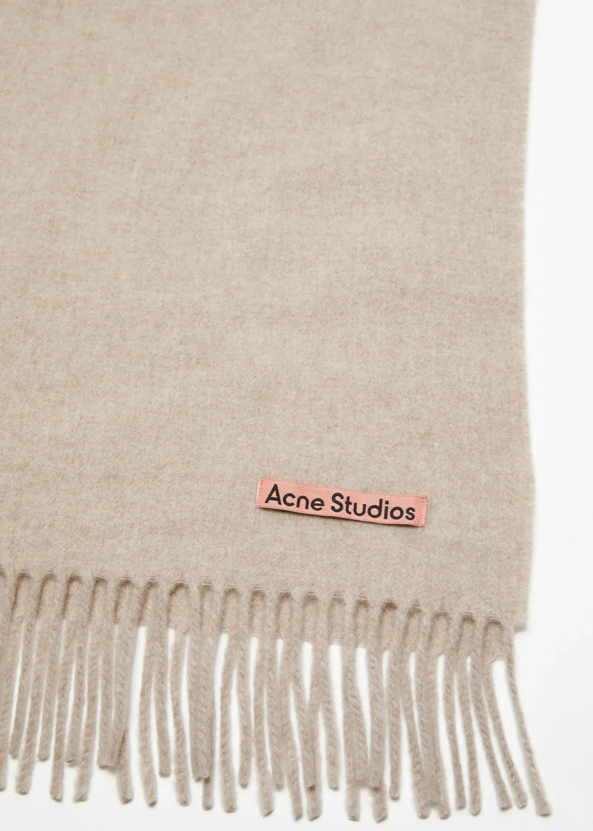 Fokus auf das rosa Logo-Etikett mit Acne Studios Schriftzug und die ausgefransten Enden des Schals.