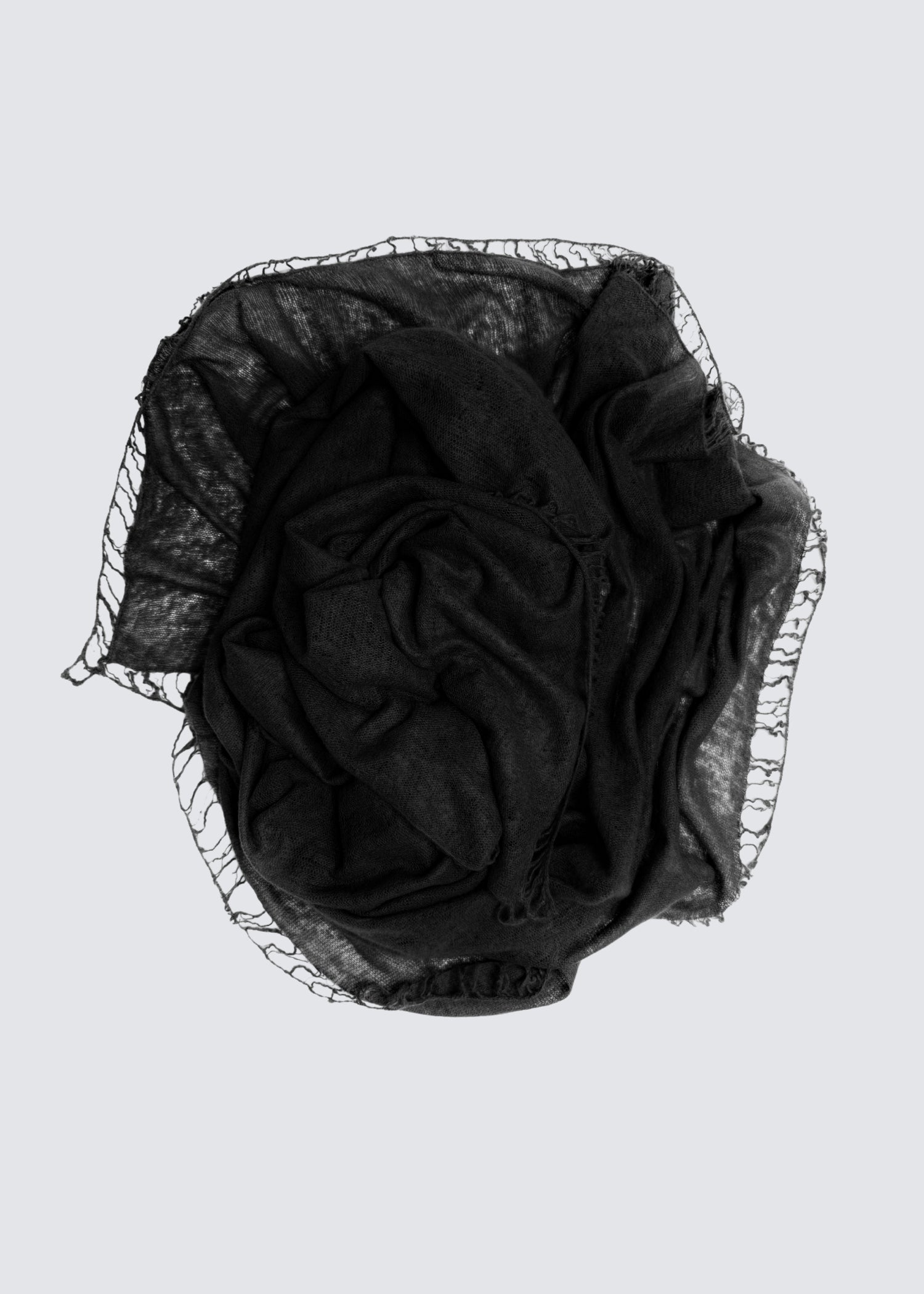 Zusammengerollter Kaschmirschal in Schwarz. Gefranste Enden. Flatshot