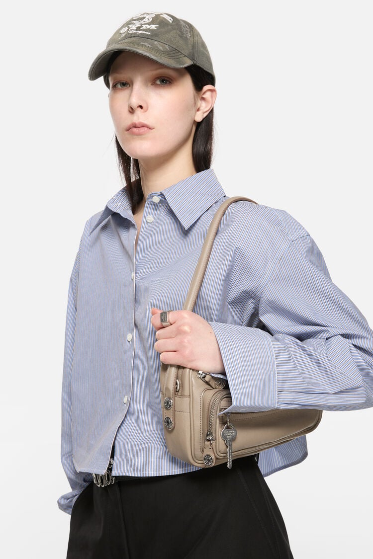 Beige Baguette Tasche mit Reisverschluss Details. Schlüsselanhänger an vorderem Reisverschluss Fach. Trage Bild.