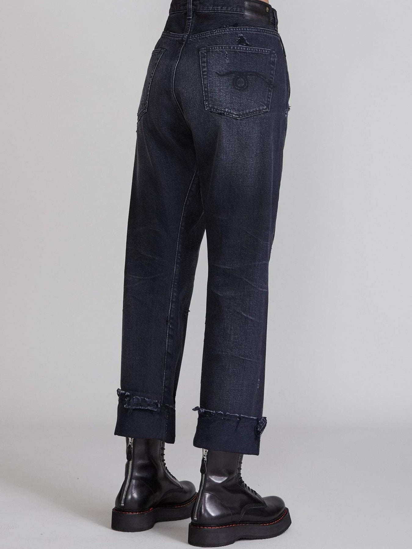 Das Model trägt die R13 Cross Over Jeans in Jake Black, Rückansicht.