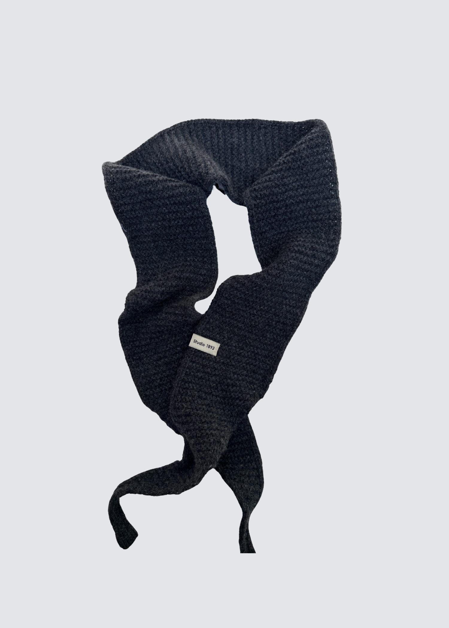 Gestrickter schmaler Schal in Anthrazit . Spitz zulaufend. Dezentes Studio 1893 Logo am Ende des Schals. Flatshot.