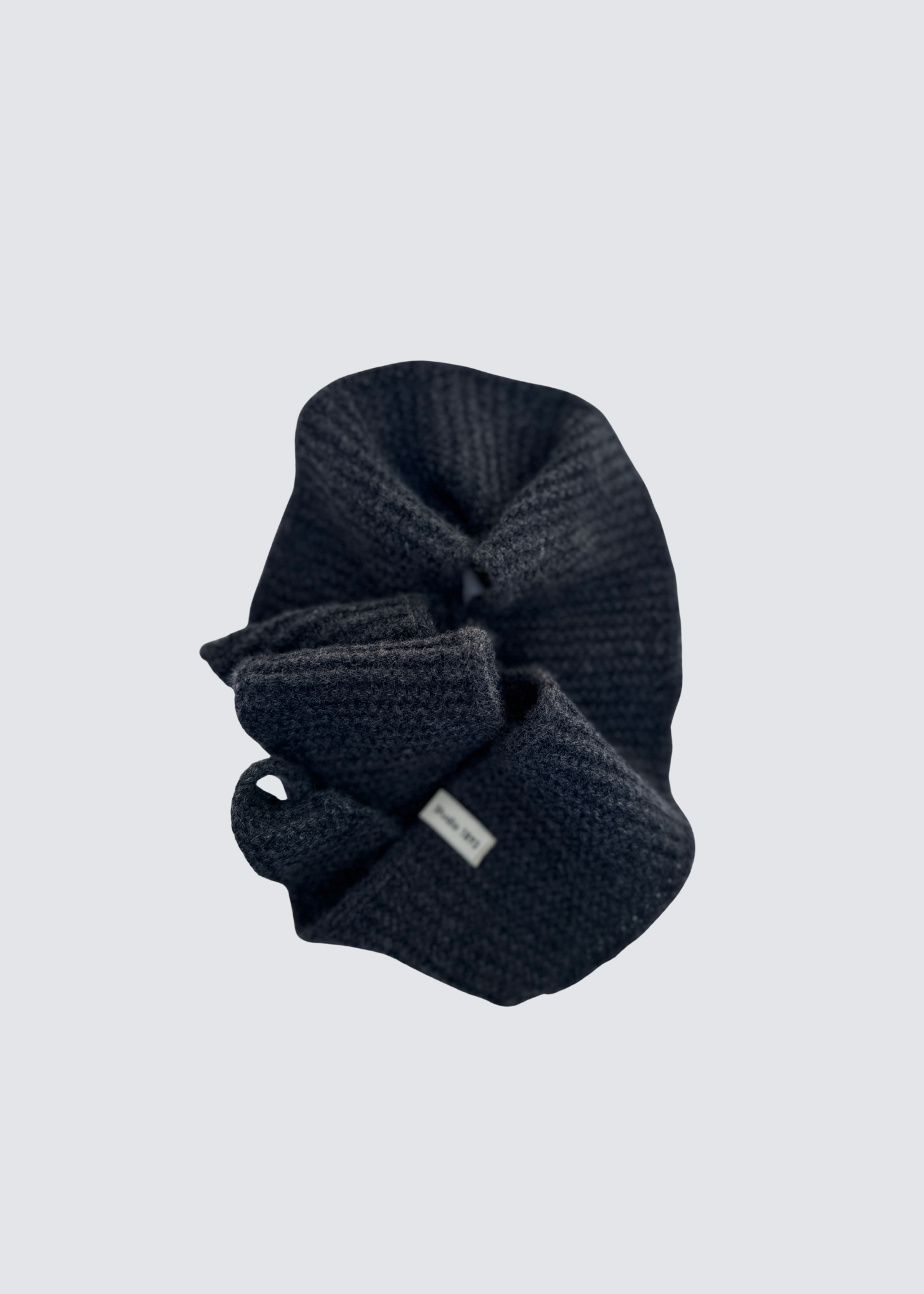 Gestrickter schmaler Schal in Anthrazit . Spitz zulaufend. Dezentes Studio 1893 Logo am Ende des Schals. Flatshot, gewickelt.