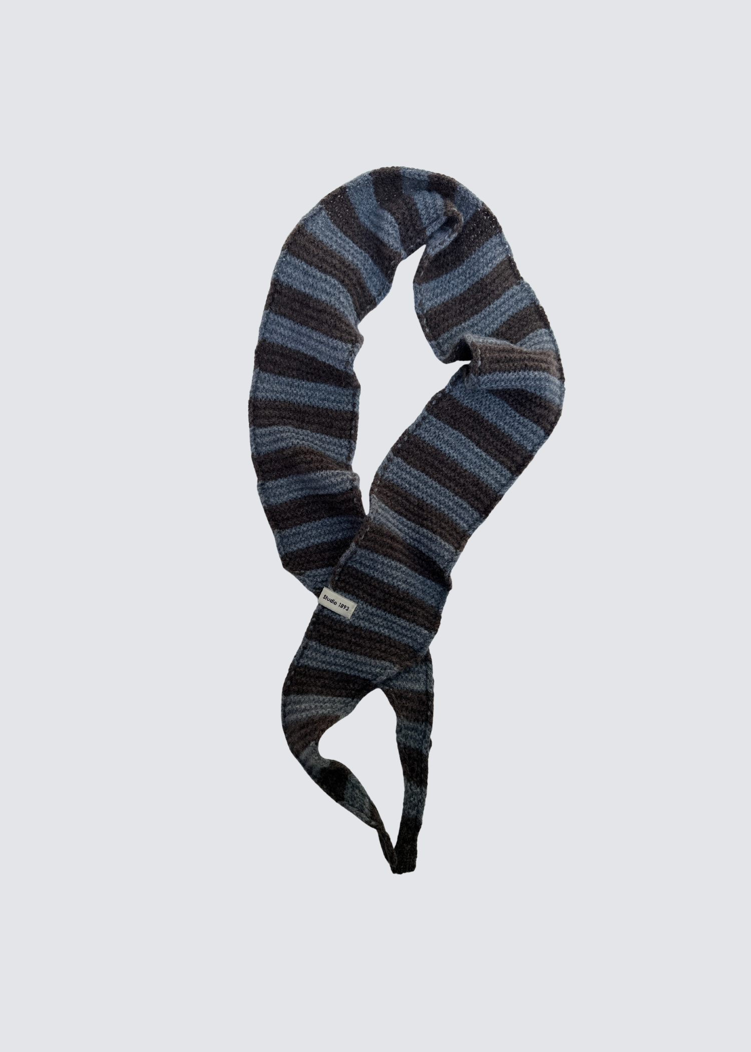 Gestrickter schmaler Schal in Braun und Grau. Spitz zulaufend. Dezentes Studio 1893 Logo am Ende des Schals. Flatshot. 
