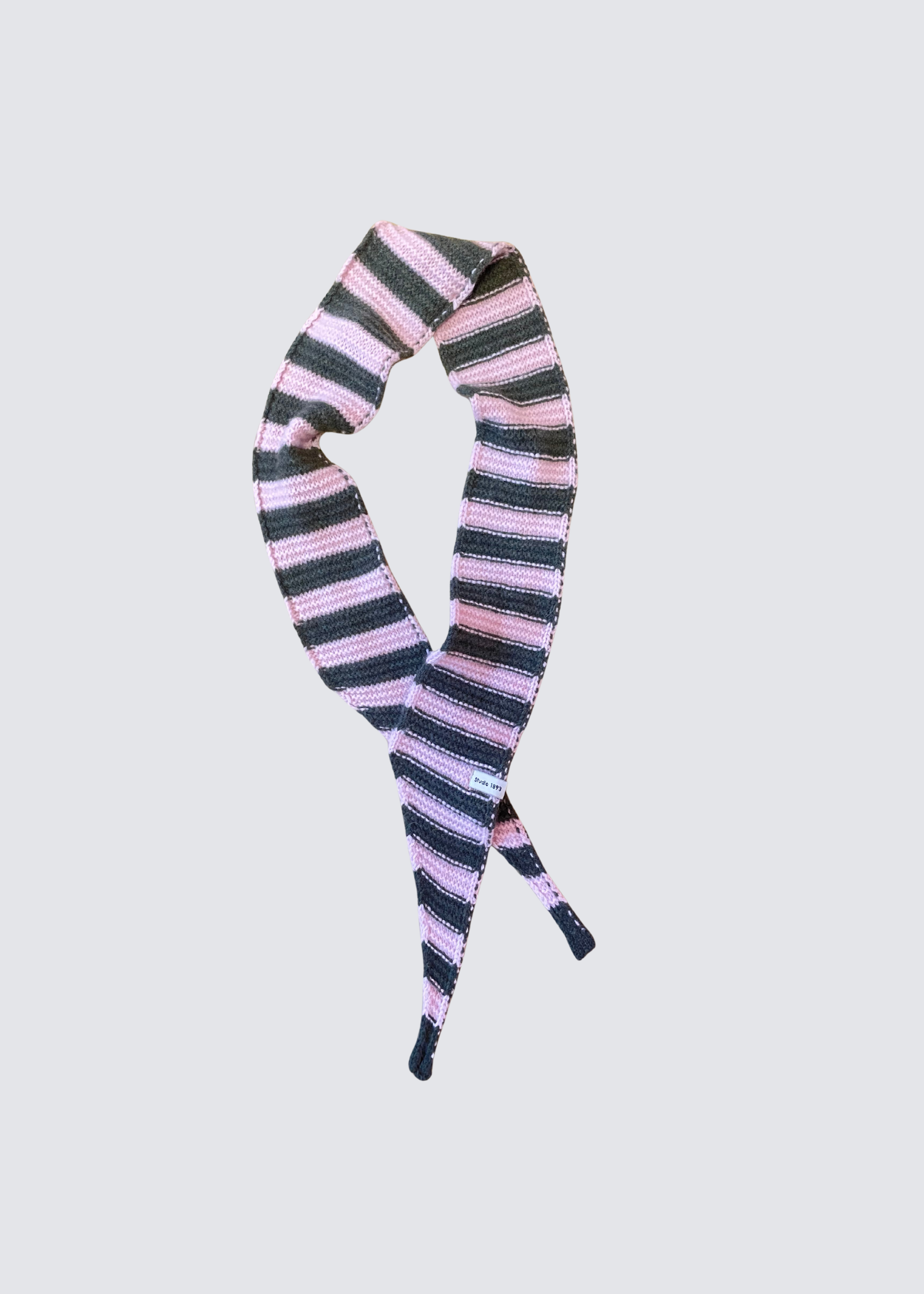 Gestrickter schmaler Schal in Olive und Rosa. Spitz zulaufend. Dezentes Studio 1893 Logo am Ende des Schals. Flatshot. 