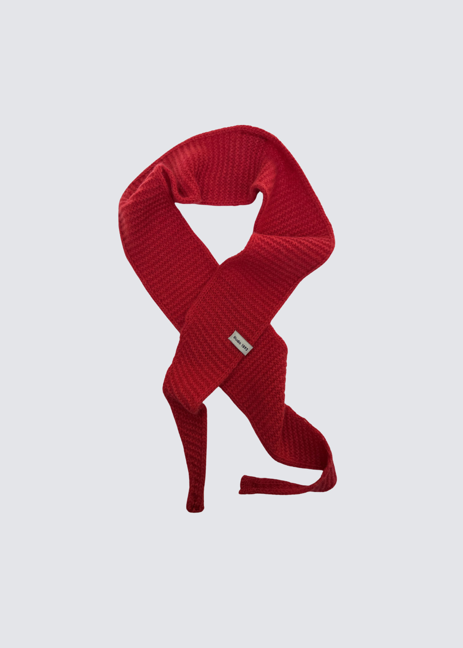 Gestrickter schmaler Schal in Rot . Spitz zulaufend. Dezentes Studio 1893 Logo am Ende des Schals. Flatshot.