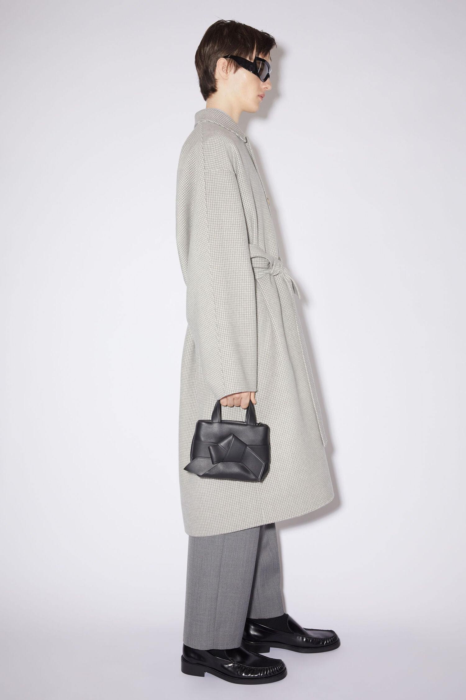 Schwarze Micro Bag mit Schleifen Detail auf der Vorderseite. Model Bild.