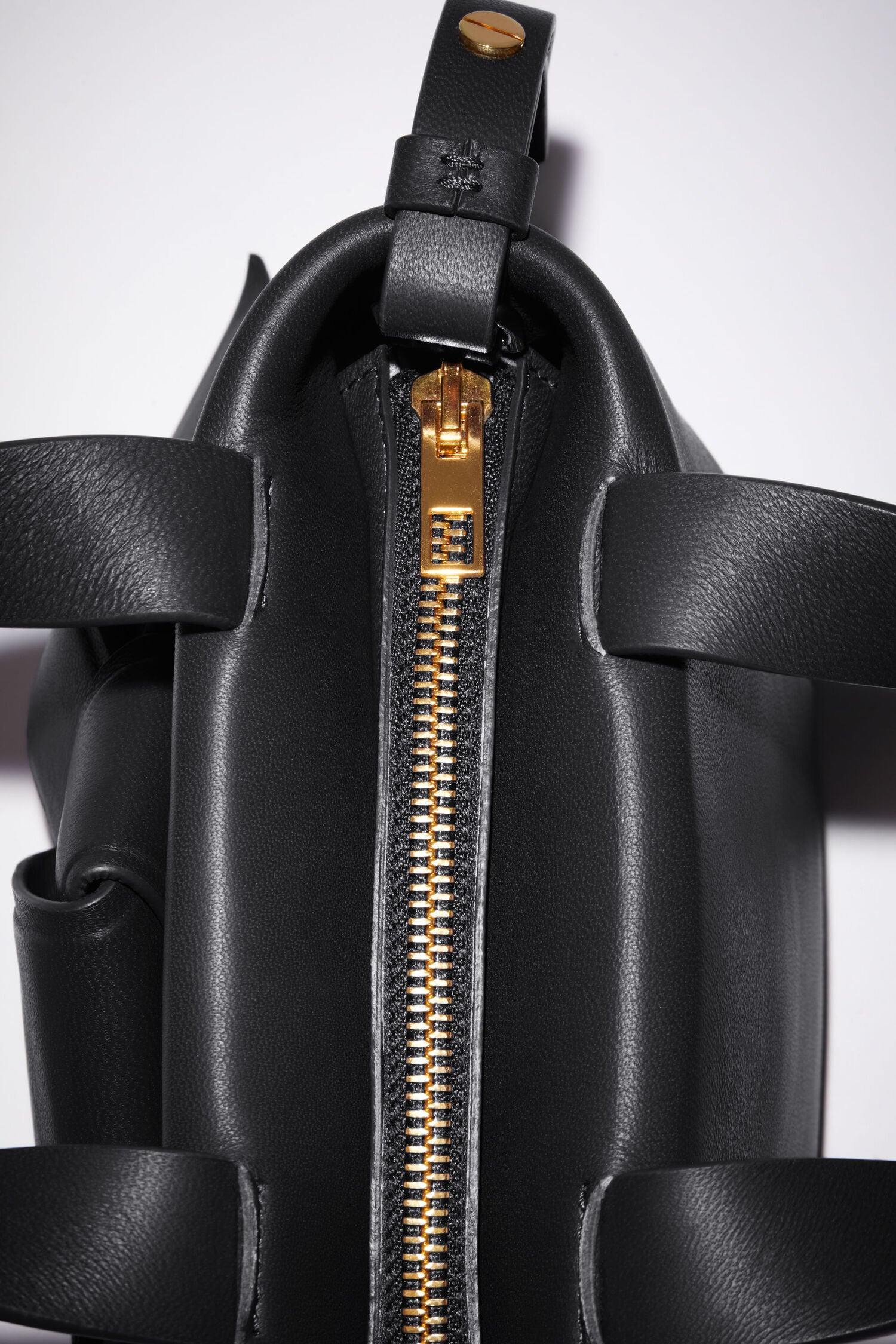 Schwarze Micro Bag mit Schleifen Detail auf der Vorderseite. Reißverschluss Detail Shot.